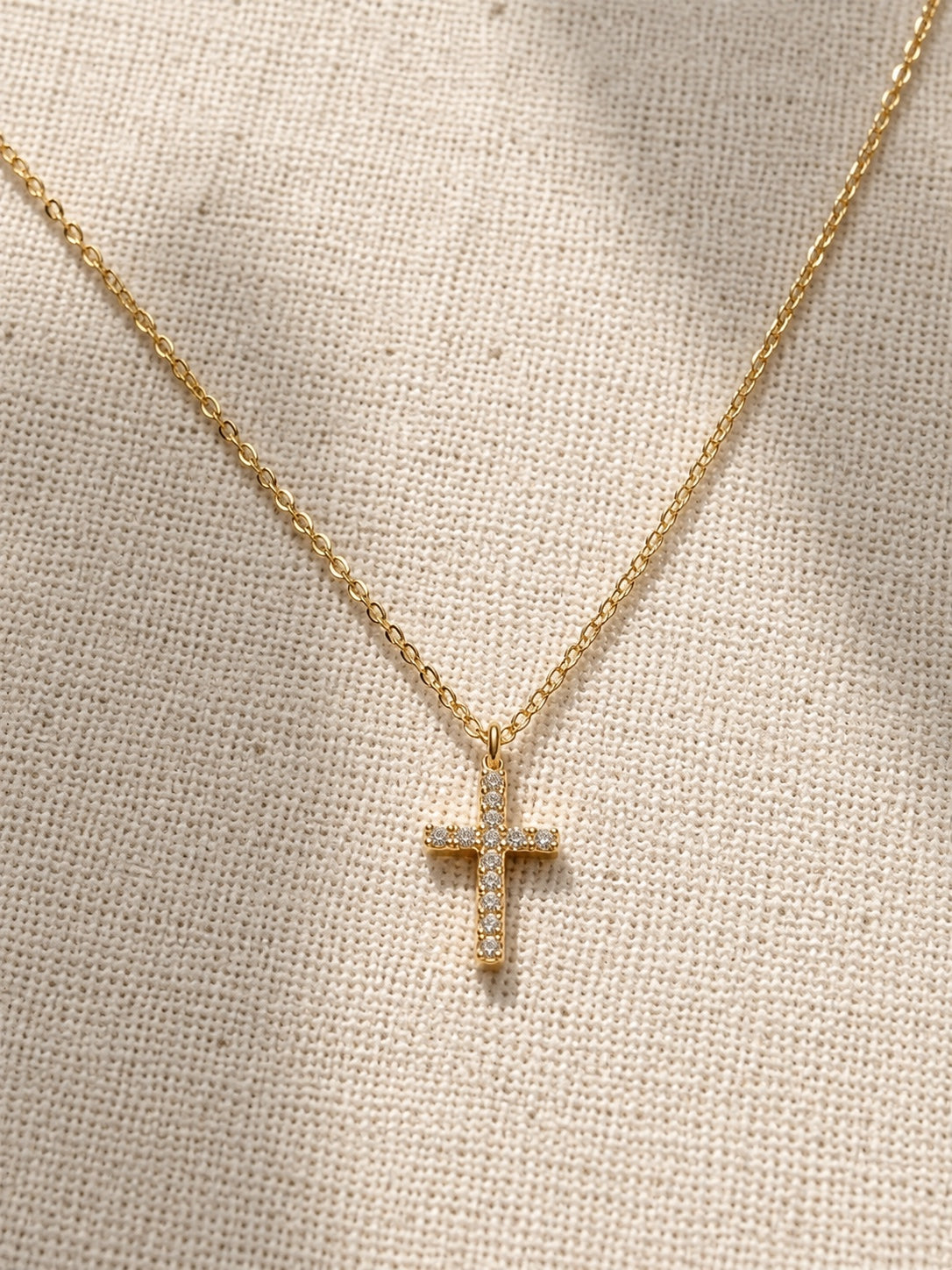 Détail collier croix doré sur fond lin SOA Edition